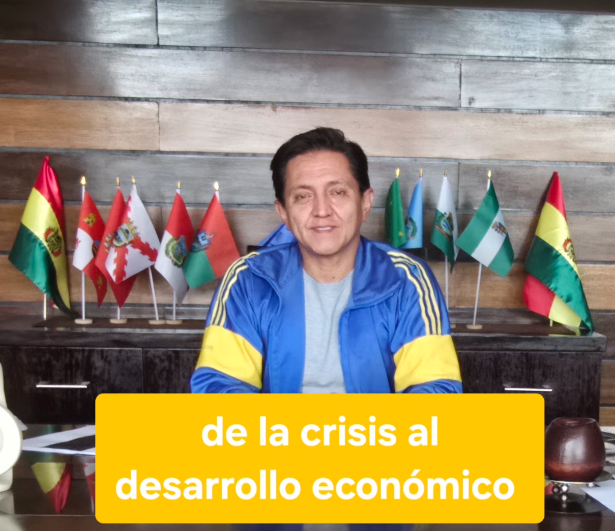 Pavel Aracena grabando un video sobre 'de la crisis al desarrollo económico' con chamarra deportiva azul y amarilla